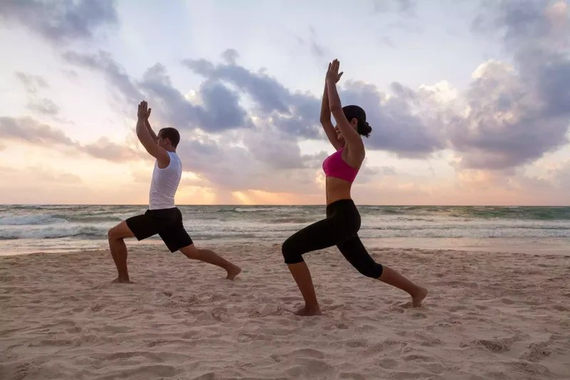 Pareja practicando yoga en la playa