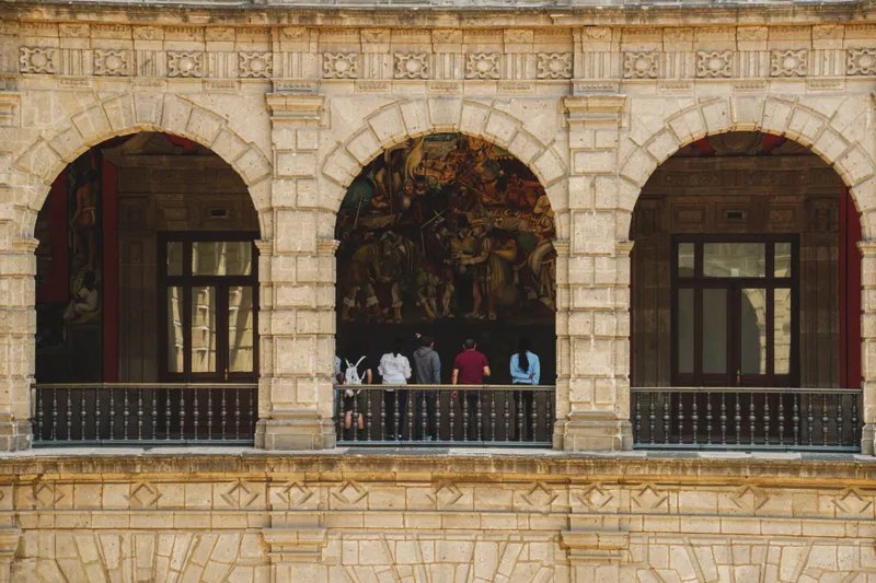 Gente mirando el mural en el interior del Palacio Nacional