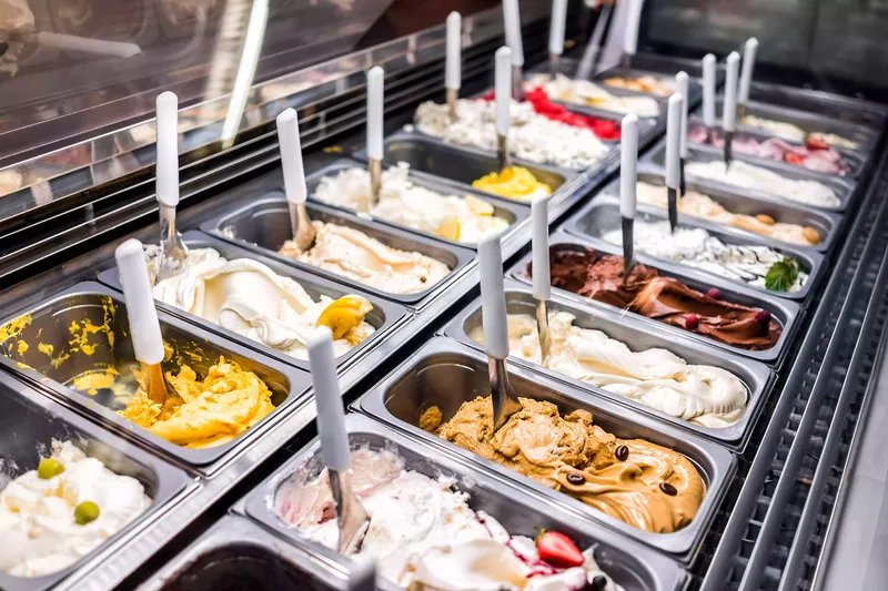 Mostrador de helados Frozen Yogurt de colores con muchos sabores de cuchara, sorbete, chocolate, toppings, café
