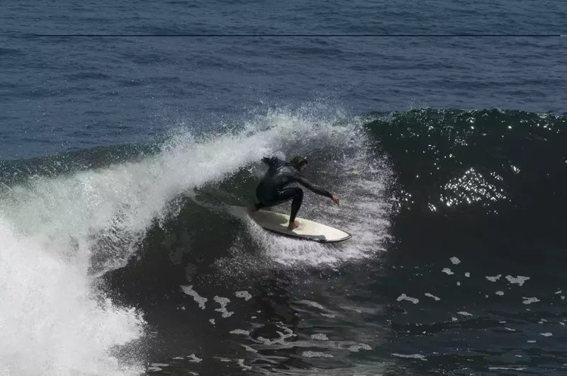 Un hombre con traje de neopreno surfeando en Punta de Lobos, Pichilemu, Chile