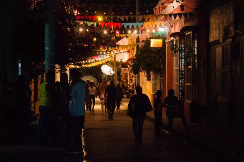 Gente caminando por una calle iluminada de noche en Cartagena